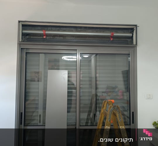 סולם מול חלון תריסים בתהליך התקנה